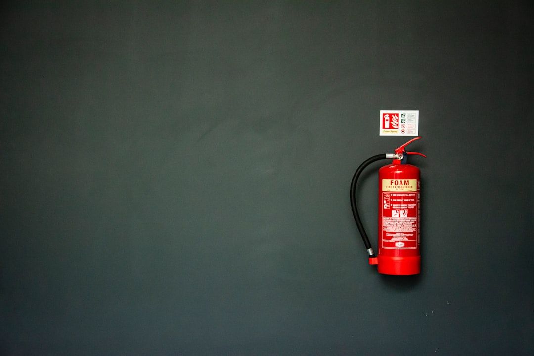 En röd brandsläckare monterad på en mörkgrå vägg.