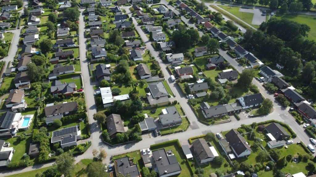Flygbild över villaområde med tomter, vägar och grönområden
